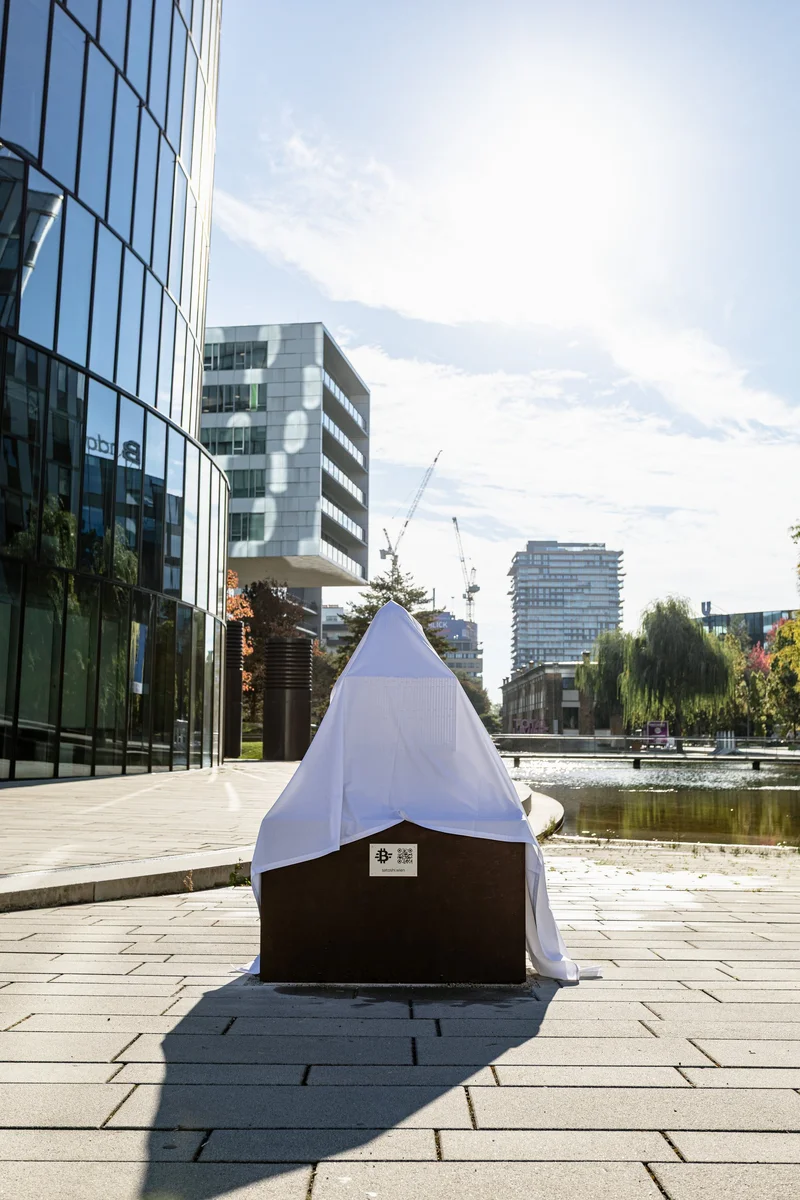 The Satoshi sculpture at Viertel Zwei the day before the unveiling, veiled under a white cloth on its Corten steel base.